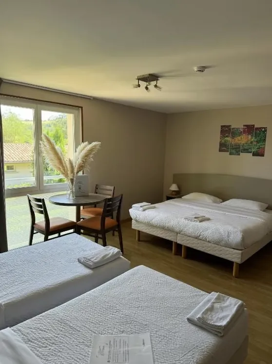 Chambre avec un grand lit, deux lits simples et une table