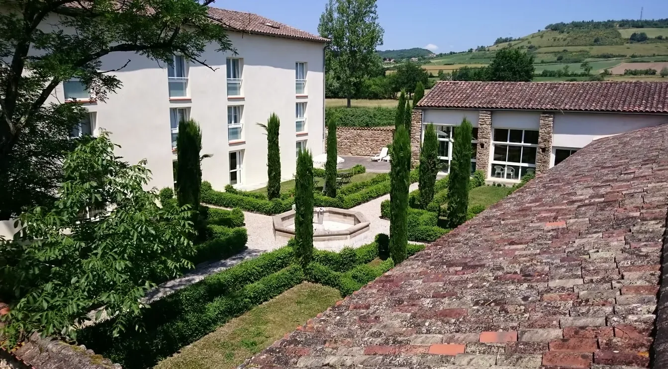 Cour intérieure avec fontaine, cyprès et haies de buis, collines au fond