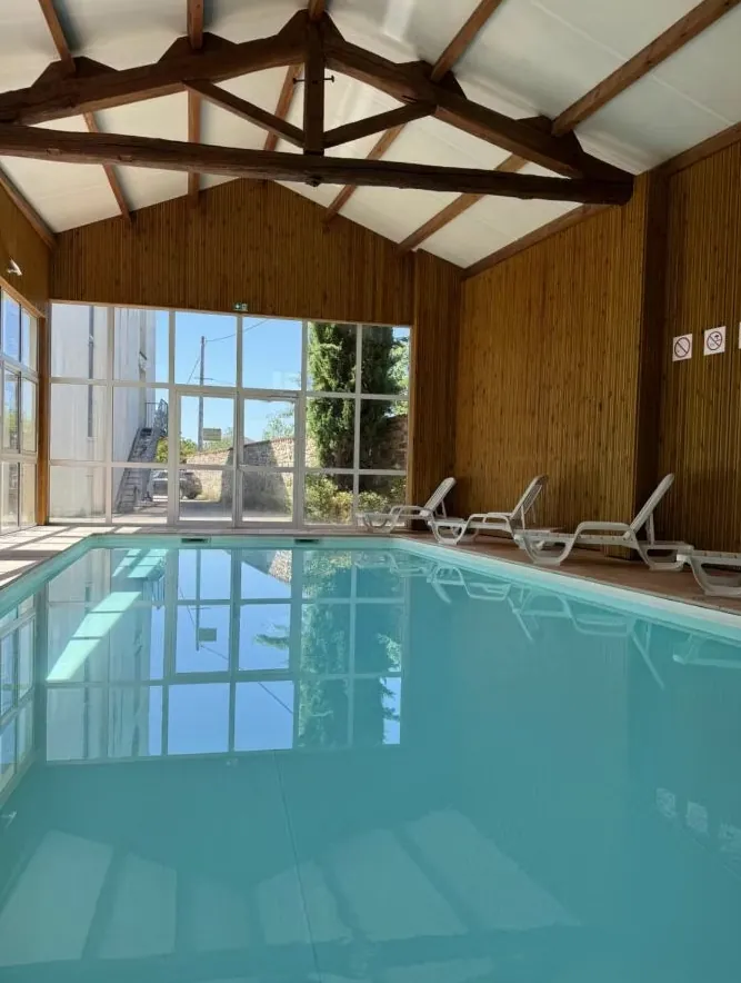 Piscine couverte avec charpente en bois et transats